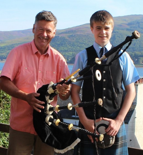 Image from BBC Scotland of Bob Worrall presenting the pipes to Calum McKillop in summer 2016